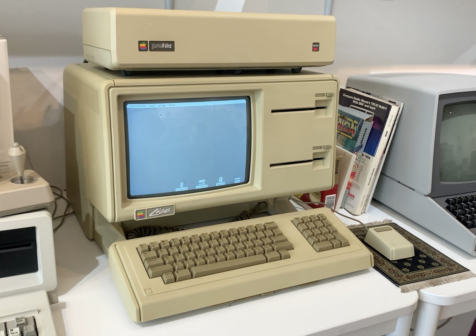 An Apple Lisa computer: a tall beige all-in-one with a built-in monochrome display above two floppy drive slots and a detached keyboard.